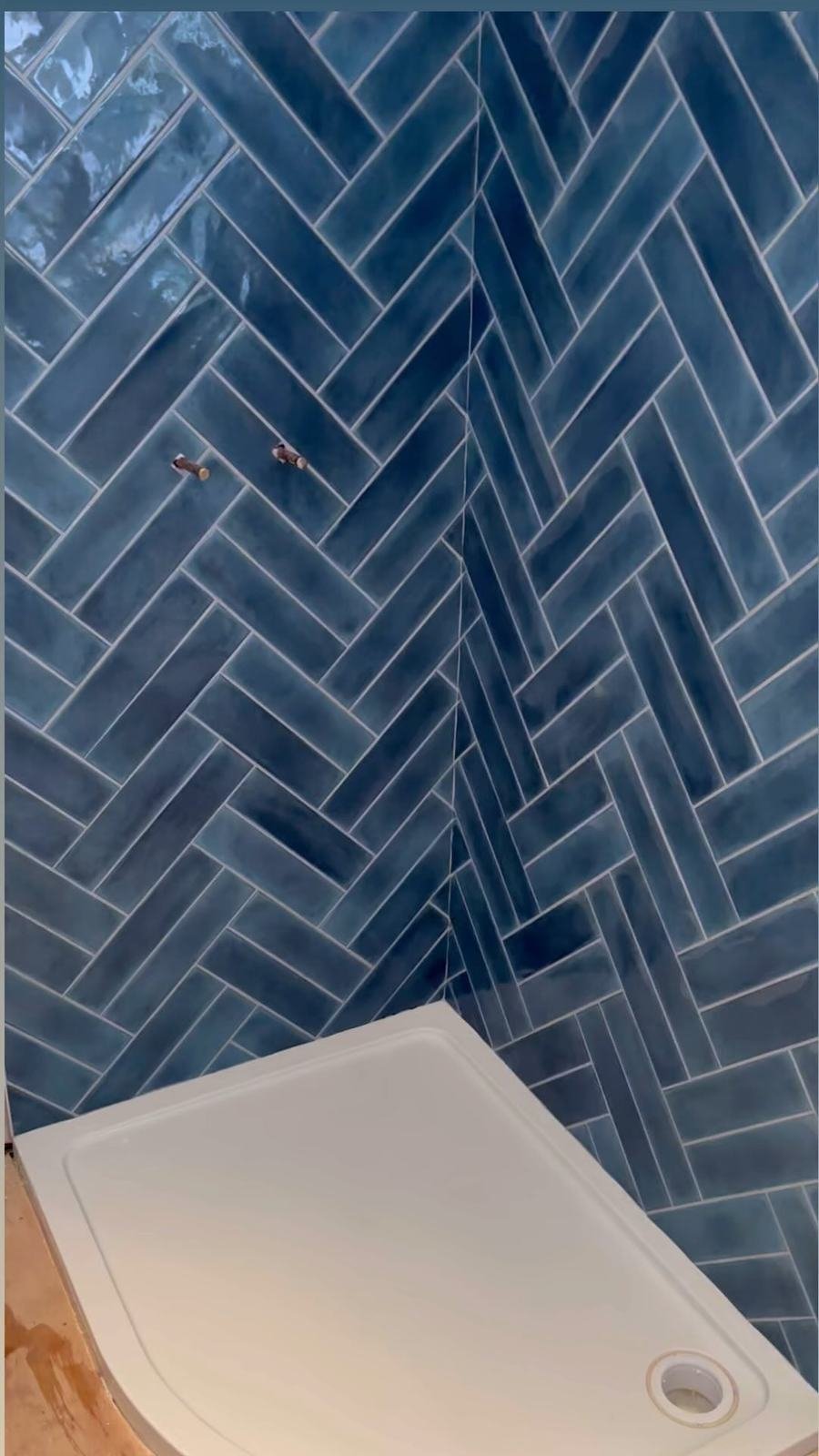 Blue gloss tiles in double herringbone on a shower wall