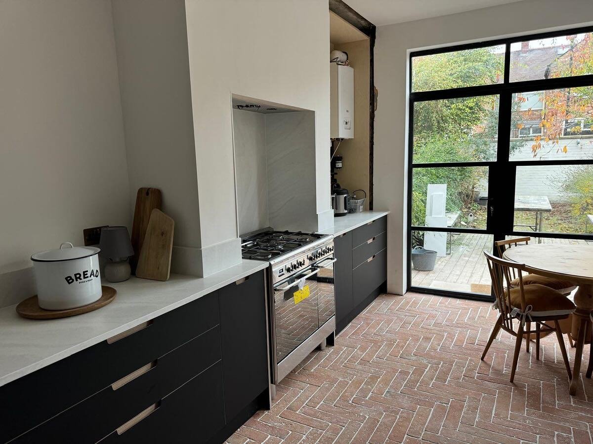 Kitchen with terracotta herringbone floor, dark units and a range cooker