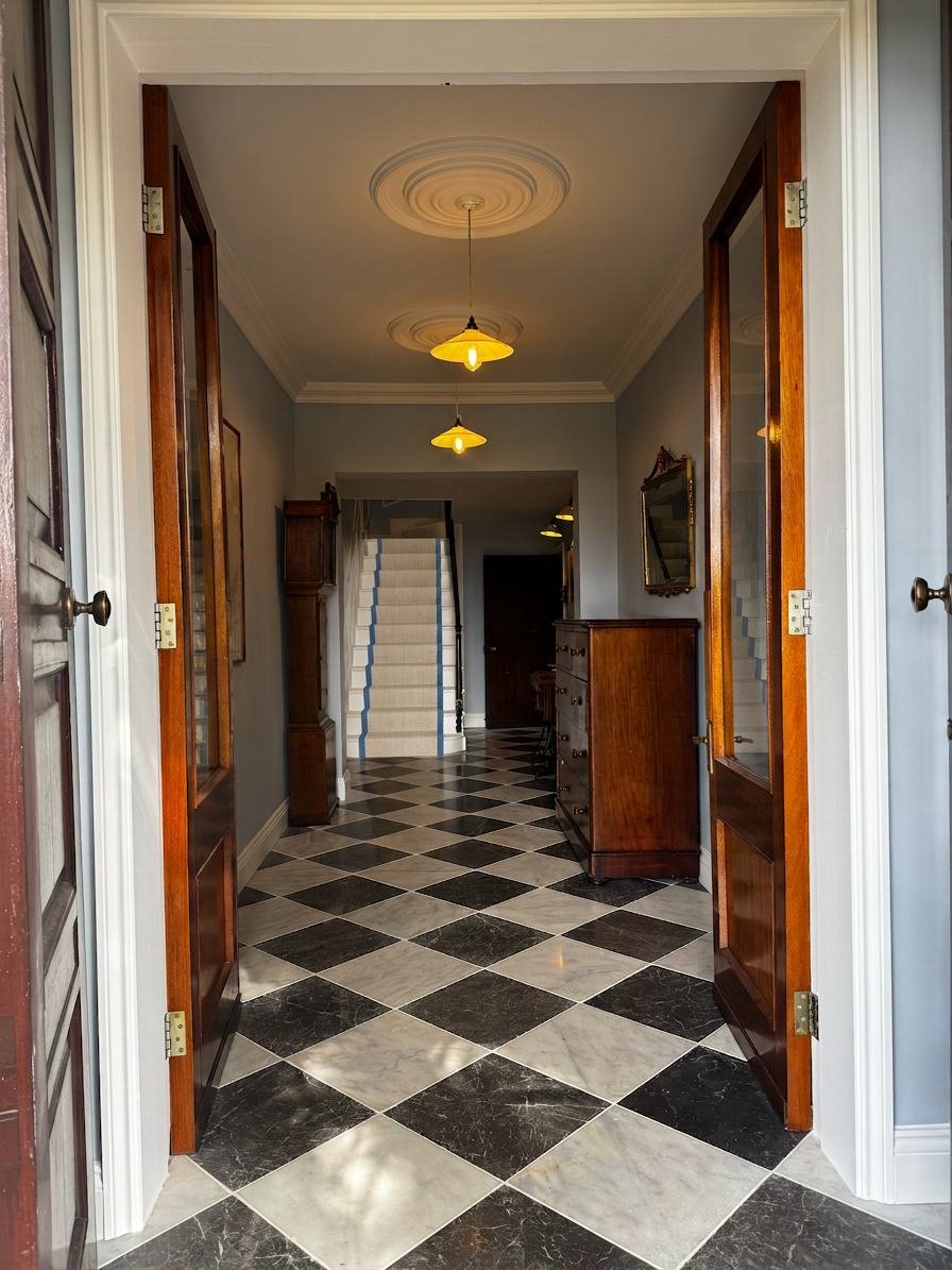 Hallway with a black and white marble chequerboard floor leading to the stairs