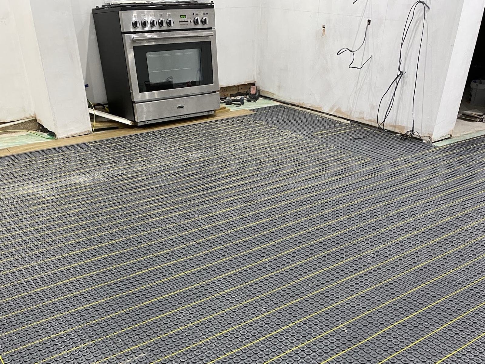 Before: kitchen floor covered in an uncoupling mat with underfloor heating cable laid in loops