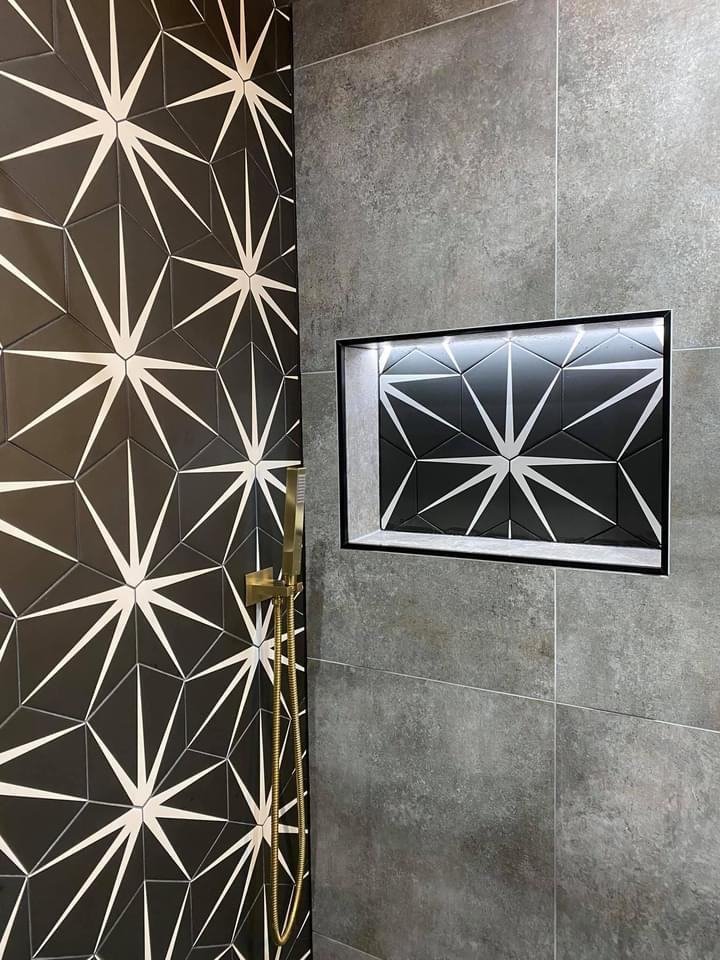 Shower wall with a black and white star-pattern feature strip and niche