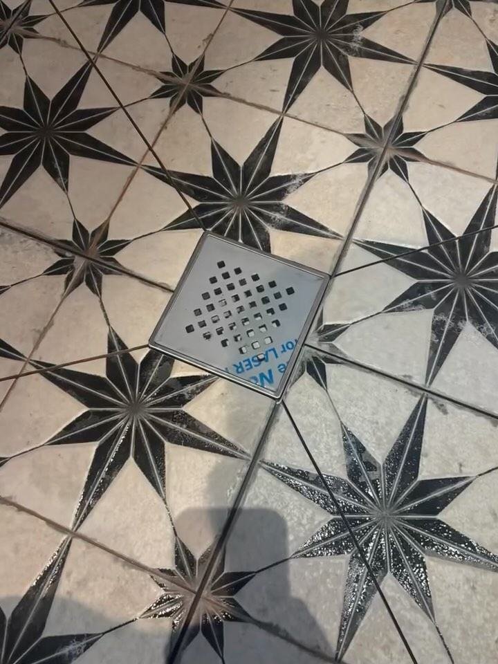 Wet room floor in star-pattern tiles around a square drain